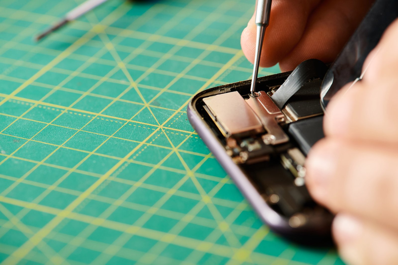 partial view of technician opening smartphone with screwdriver for diagnostics in repair shop